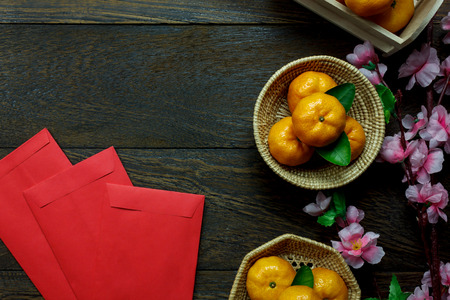 Top view accessories Chinese new year festival decorations.orange,leaf,wood basket,red packet,plum blossom on table wooden background with copy space.の写真素材
