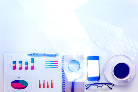 Top view accessories business office desk .mobile phone,coffee,notepaper,pencil,laptop,eyeglasses,chart on white office desk with copy space.の写真素材