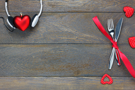 Top view valentines day and music background.dinner set and love music fork knife red ribbon headphones and heart shape on wooden with copy space.の写真素材