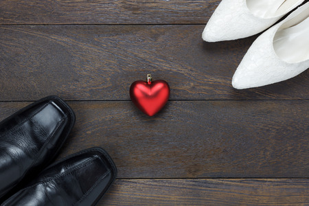 Top view heart shape with men's shoes and women's shoes on wooden background.の写真素材