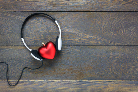 Top view red heart shape listening music with headphones on wooden background and copy space.の写真素材