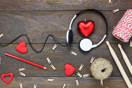 Top view red heart shape listening music by headphones with decorations drun stick,pencil,rope  on wooden background and copy space.の写真素材