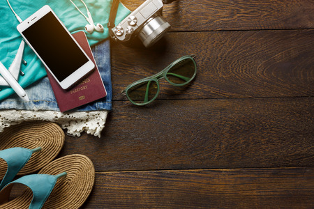 Top view accessories  travel with mobile phone,camera,sunglasses,cloth woman,sandal on table wooden with copy space.Travel concept.の写真素材