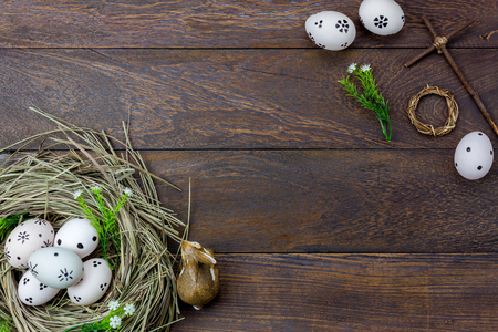 Top view easter background.Happy easter eggs pained also rabbin and cross on nest.Texture rustic wooden with decorations flowers and copy space.の写真素材