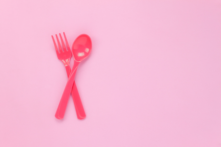 Top view colorful plastic spoon on pink table background with copy space.