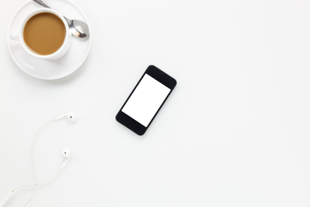 Top view  accessories office desk.smartphones earphones and cup of coffee on white background.の写真素材