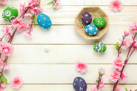 Top view easter background.Happy easter eggs pained on basket also beautiful pink flower.Texture rustic white wooden with decorations and copy space.の写真素材