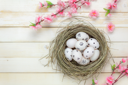 Top view easter background.Happy easter eggs pained on nest also beautiful pink flower.Texture rustic white wooden with decorations and copy space.の写真素材