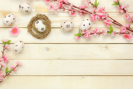 Top view easter background.Happy easter eggs pained on nest also beautiful pink flower.Texture rustic white wooden with decorations and copy space.の写真素材