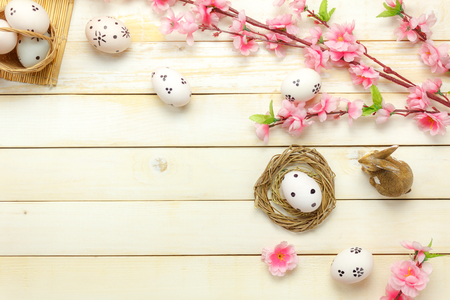 Top view easter background.Happy easter eggs pained on nest also beautiful pink flower with rabbit doll.Texture rustic white wooden with decorations and copy space.の写真素材