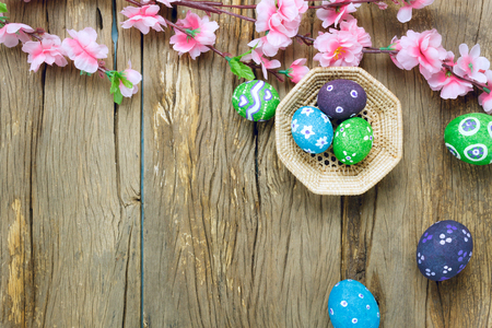 Top view easter background.Happy easter eggs pained on nest also beautiful pink flower.Texture rustic  wooden with decorations and copy space.の写真素材