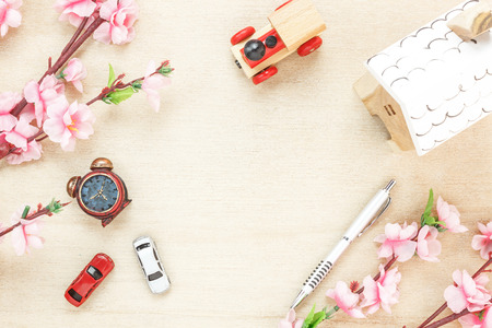 Top view business office desk concept. Wood house  also car and clock on wooden shelf.The beautiful pink flower with pen on wood background with copy space.の写真素材