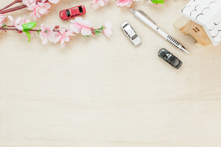 Top view business office desk concept. Wood house  also car and clock on wooden shelf.The beautiful pink flower with pen on wood background with copy space.の写真素材