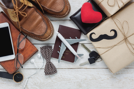 Top view Happy Father day with travel concept. Airplane and passport on rustic wooden background. accessories with red heart,mustache,vintage bow tie,pen,present,white mobile phone,shoes ,earphone,watch and notebook.の写真素材