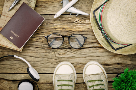 Top view essential travel items.The shoes notebook tree map passport airplane car eyeglasses on rustic  wooden background.の写真素材