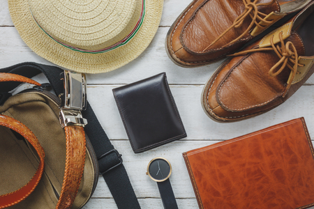 Top view accessoires to travel with man clothing concept. wallet on wooden background.watch,bag,hat,notebook and shoe on white wood table.の写真素材