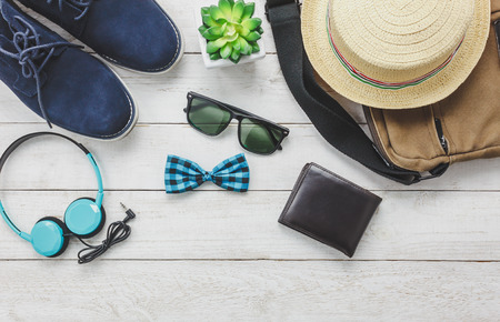 Top view accessoires to travel with man clothing concept. headphone on wooden background.bow tie,wallet,sunglasses,shoe,bag and hat on wood table.の写真素材