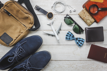Top view accessories man fashion to travel concept.Airplane and earphone on wooden background.man's shoe,bag,bow tie,map,passport,watch,notebook on wood table.flat lay.copy space.の写真素材