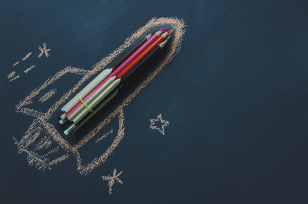 Top view rocket fling on the space with star.Crated by colorful pencil and drawing by chalk board on backboard or table.Start up business.Back to school and education concept.flat lay.copy space.の写真素材