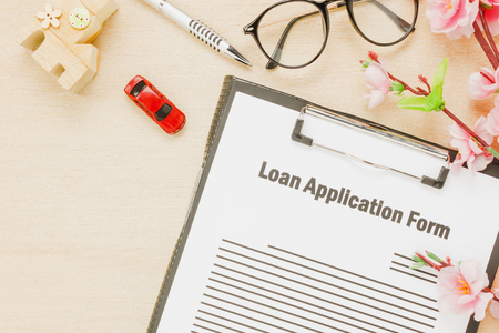 Top view business office desk background.The business loan appcation form pen flower house and car  on wooden table background with copy space.の写真素材