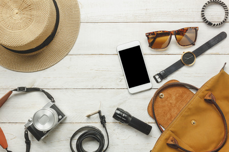 Top view / Flat lay accessoire to travel and technology with woman / lady clothing on white wooden tableの写真素材
