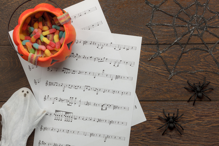 Above view of  Happy Halloween Festival and music note sheet background concept.Trick or treat bowl and decorations items on modern brown table.Mix variety object idea for season with copy space.の写真素材