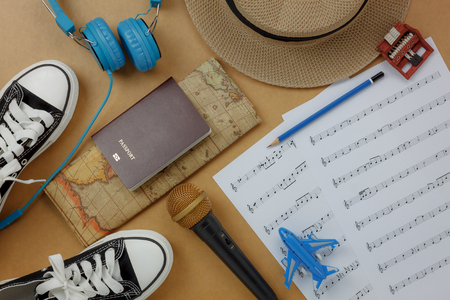 Above view of the accessories to travel and music sheet concept background.Music note and items for traveler and adult or teen.Difference objects on modern rustic brown wood at home office desk.の写真素材