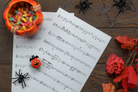 Top view of  Happy Halloween Festival and music note sheet background concept.Trick or treat bowl and decorations items on modern brown table.Mix variety object idea for season with copy space.の写真素材