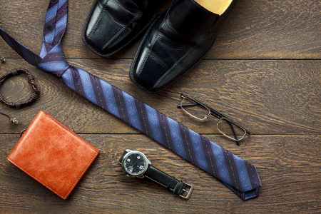 Overhead shot of fashion men lifestyle concept background.Leather black shoe & wallet with essential accessory to travel on modern rustic brown table at home office desk.Copy space for design.の写真素材
