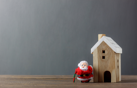 Santa Claus and white wooden home on modern rustic brown wood.Essential decorations & Ornaments of Merry Christmas in winter season concept.Several accessories decor festival.Free space for wording.の写真素材