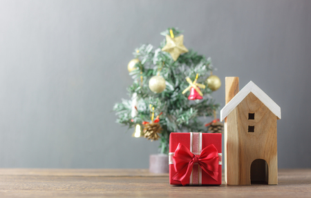 Beautiful red gift box and wooden white house.Blur background Christmas tree and decoration & ornament.Merry Christmas ans winter season concept.Several accessories on modern rustic brown wooden.の写真素材