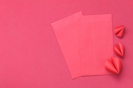Table top view of accessories on Lunar New Year & Chinese New Year vacation concept background.Red packet money and DIY paper craft fortune cookies on modern rustic red backdrop at home office desk.の写真素材