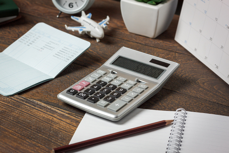 Essential accessory of  business finance & savings economy on office desk background concept.Close up calculator to plane travel with items on modern rustic brown wooden at home table studio.の写真素材