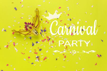 Table top view aerial image of beautiful yellow carnival mask background.Flat lay accessory object on modern yellow paper at home office desk studio.Creative design text for the festival backdrop.の写真素材