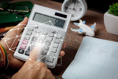 Business or finance background concept.Close up man calculate payment or money for plan to travel all world with saving banking on modern rustic brown office desk.Idea for traveler for global trip.の写真素材