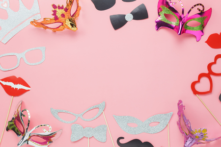 Table top view aerial image of beautiful carnival party mask or photo booth props background.Flat lay many objects on modern rustic pink paper at office desk studio.space for creative design mock up.の写真素材