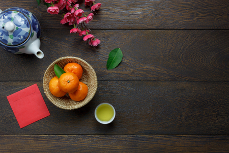 Top view aerial image of accessory decoration Chinese new year & lunar holiday background concept.Flat lay Orange & flower also red pocket money.Variety object on modern brown wood at office desk.