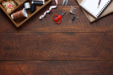 Flat lay aerial image of fashion designer items background concept.Top view sewing accessory or tailor equipment on modern rustic brown wooden at home office desk studio.Crafting tools in work shop.の写真素材