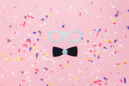 Table top view aerial image of beautiful carnival mask or photo booth props background.Flat lay glasses & gentleman bow tie on modern rustic pink paper at office desk studio.space for creative design.の写真素材