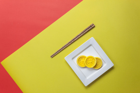 Top view shot of arrangement decoration Chinese new year & lunar festival concept background.Dessert of the season in plate with wood chopsticks.Objects on modern yellow & red paper at office desk.の写真素材
