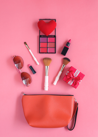 Table top view accessory of clothing women plan to travel in holiday background.Beauty & Fashion concept.Flat lay of hand bag with many essential items cosmetic and sun glasses on modern pink paper.の写真素材