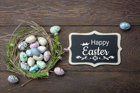 Table top view shot of decoration Happy Easter holiday background concept.Flat lay bunny egg with blossom at bird's nest on modern brown wooden at office desk. blackboard design text welcome to seasonの写真素材