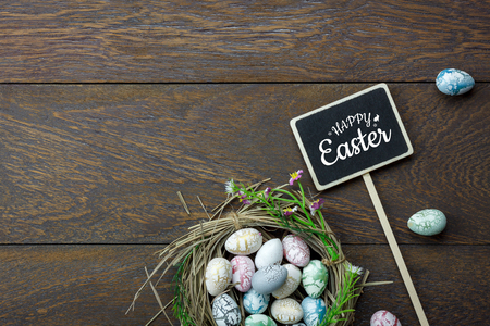 Table top view shot of decoration Happy Easter holiday background concept.Flat lay bunny egg with tulip flower and rabbit doll on modern brown wooden at office desk.Blank space blackboard for mock up.の写真素材