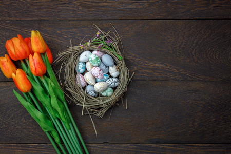 Table top view shot of decoration Happy Easter holiday background concept.Flat lay bunny egg with tulip flower and accessory on modern rustic brown wooden at office desk.Blank space for mock up.の写真素材