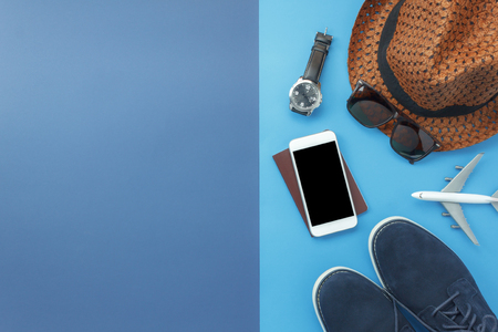 Table top view accessory of clothing women  plan to travel in holiday background concept.Mobile phone with many essential  items hat & shoes on modern rustic duo blue paper with space creative design.の写真素材