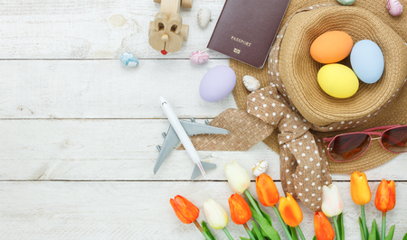 Table top view shot of decoration Happy Easter holiday background with accessory woman to travel concept.Flat lay bunny egg with tulip flower and rabbit doll on modern white wooden at office desk.の写真素材