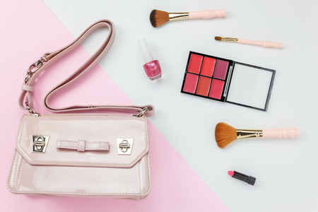 Table top view aerial image accessory of clothing women  plan to travel in holiday background concept.Hand bag with many essential  items cosmetic on modern white & pink paper.Duo with pastel tone.の写真素材