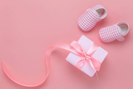 Top view aerial image of decoration Happy mothers day holiday background concept.Flat lay gift box with baby shoes on modern beautiful pink paper at home office desk.Free space for creative design.の写真素材