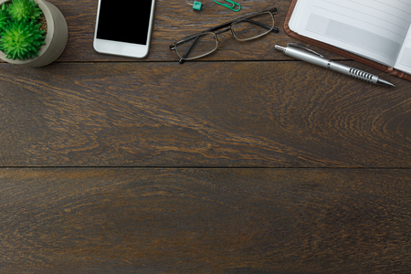 Table top view aerial image stationary on office desk background concept.Flat lay objects the mobile phone with essential accessory.Items on modern brown wooden at home studio.Space for add text.の写真素材