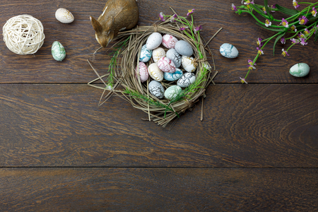 Table top view shot of decoration Happy Easter holiday background concept.Flat lay bunny egg with flower and rabbit doll on modern brown wooden at office desk.Blank space blackboard for mock up.の写真素材